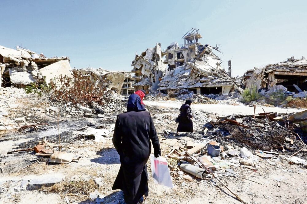 Mujeres sirias caminan entre las ruinas de la ciudad Homs. Las autoridades del país dieron por terminado el cese el fuego acordado entre EU y Rusia (YOUSSEF BADAWI. EFE)