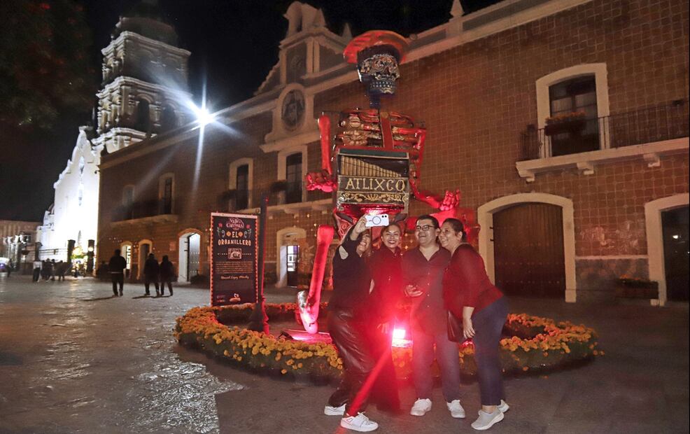 Varias personas se toman una fotografía con una calavera monumental de fondo en el municipio de Atlixco, en Puebla (México). Foto: EFE