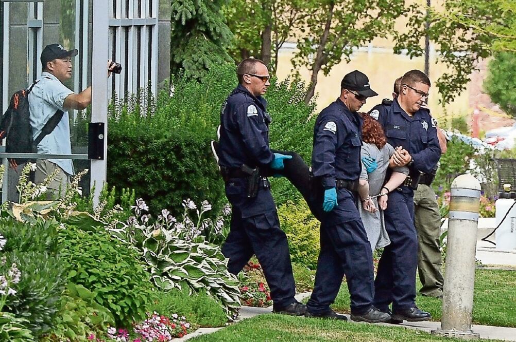 Oficiales escoltan a activistas que protestaron ayer en Oregon contra una empresa privada de prisiones que tiene contrato para detener a inmigrantes. ( AP)