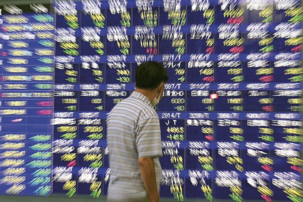 Un peatón ve información bursátil mostrada en en el centro de Tokio, donde la Bolsa cayó por tercer día consecutivo arrastrada por la de Shanghái (KIMIMASA MAYAMA. EFE)