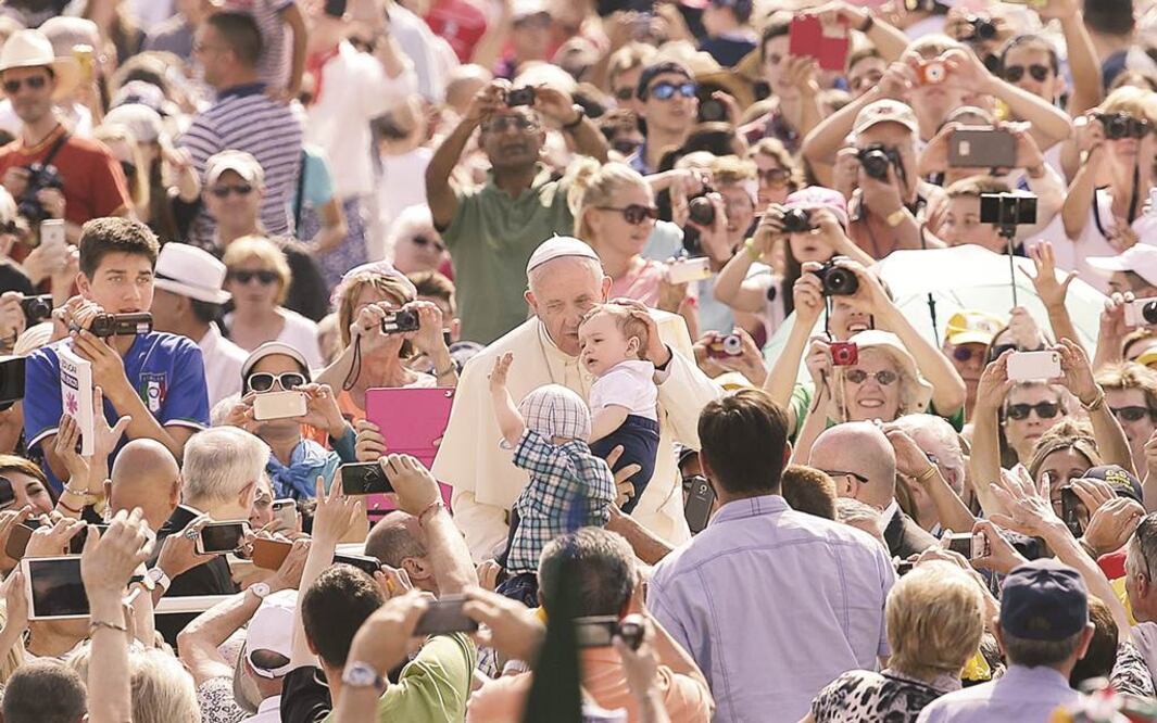 El papa Francisco besa a un bebé a su llegada a la Plaza de San Pedro, previo a la audiencia general de los miércoles, en el Vaticano. Foto Reuters