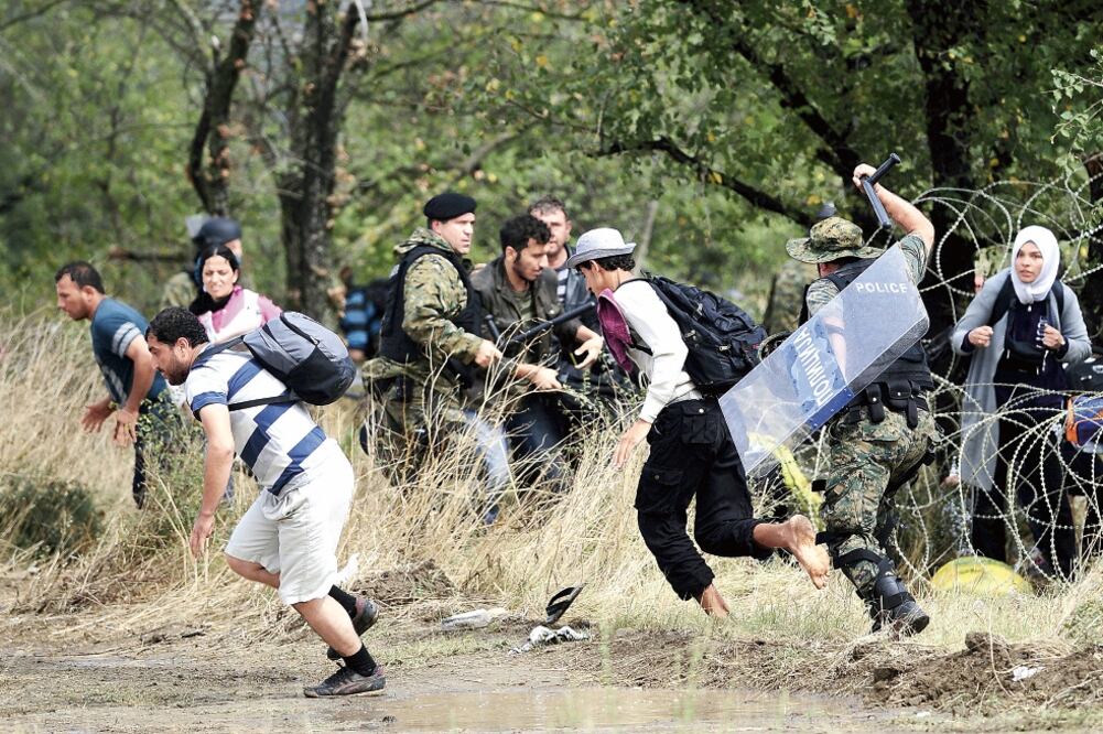 Policías persiguen a migrantes que cruzaron la frontera desde Grecia a Macedonia, cerca de la localidad de Gevgelija (OGNEN TEOFILOVSKI. REUTERS)