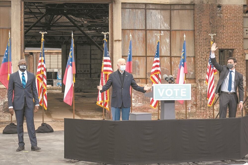 El presidente electo de Estados Unidos, Joe Biden, ayer con los candidatos demócratas al Senado, el reverendo Raphael Warnock (izquierda) y Jon Ossoff, durante un mitin en Atlanta, Georgia. Foto: DREW ANGERER. AFP