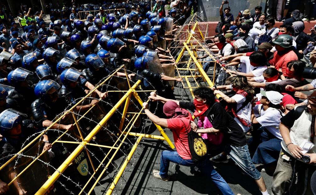 Manifestantes intenta retirar una barrera ante la policía antidisturbios durante la manifestación del Día Internacional del Trabajo en Manila. Foto: EFE