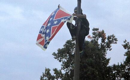Mujer escala asta y quita bandera confederada