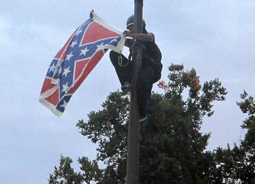 Mujer escala asta y quita bandera confederada