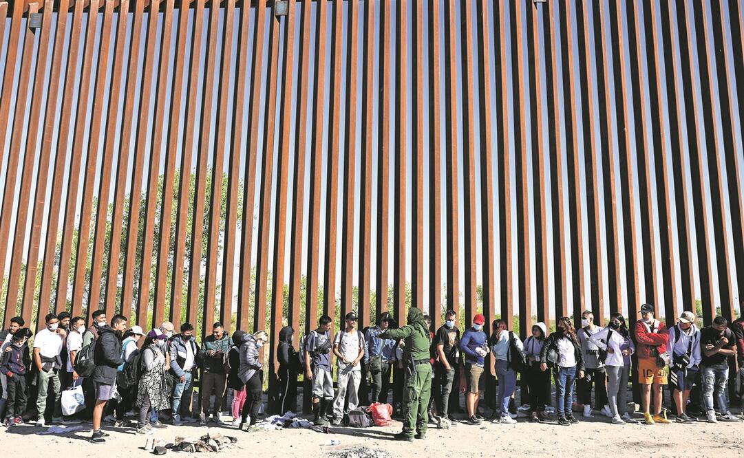 Un agente de la Patrulla Fronteriza con inmigrantes, mientras esperan para ser procesados en Yuma, Arizona.