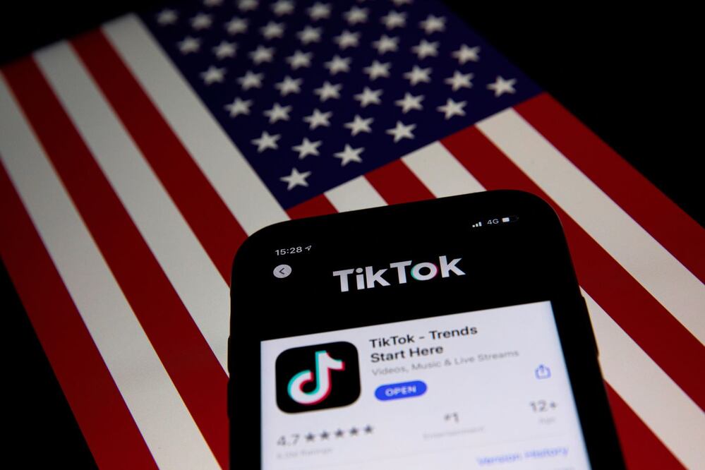 TikTok en un celular y de fondo la bandera de Estados Unidos. FOTO: EFE. ARCHIVO