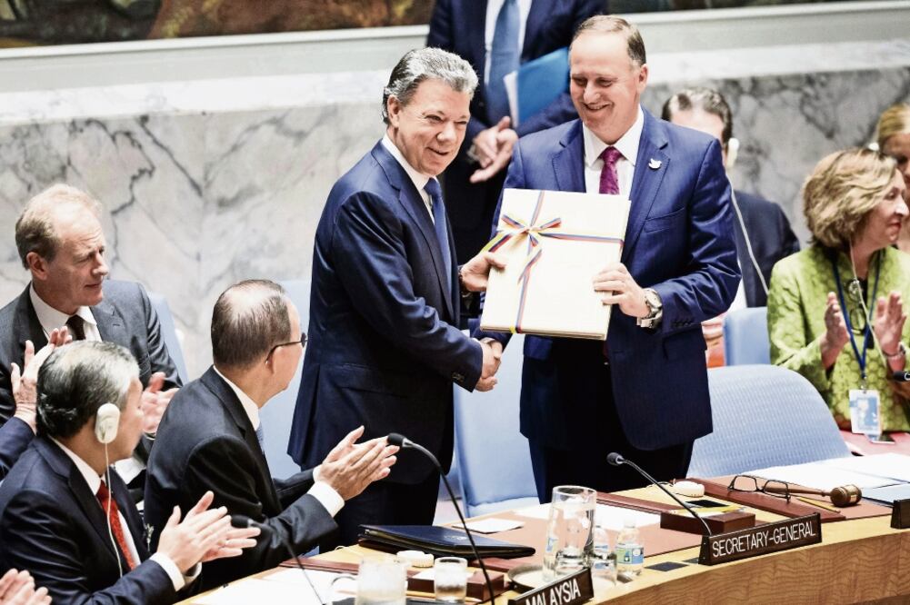 El presidente de Colombia, Juan Manuel Santos (centro-izquierda), entrega una copia del acuerdo de paz entre Colombia y las FARC al primer ministro de Nu eva Zelanda, John Key, cuyo país preside este mes el órgano de decisiones de la ONU (JUSTINE LANE)