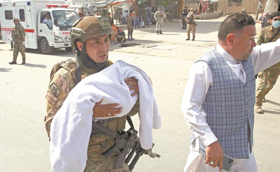 Un oficial afgano carga a un bebé, luego de un ataque en un hospital en Kabul; también hubo otro atentado durante un funeral en Nangarhar. Foto: RAHMAT GUL. AP