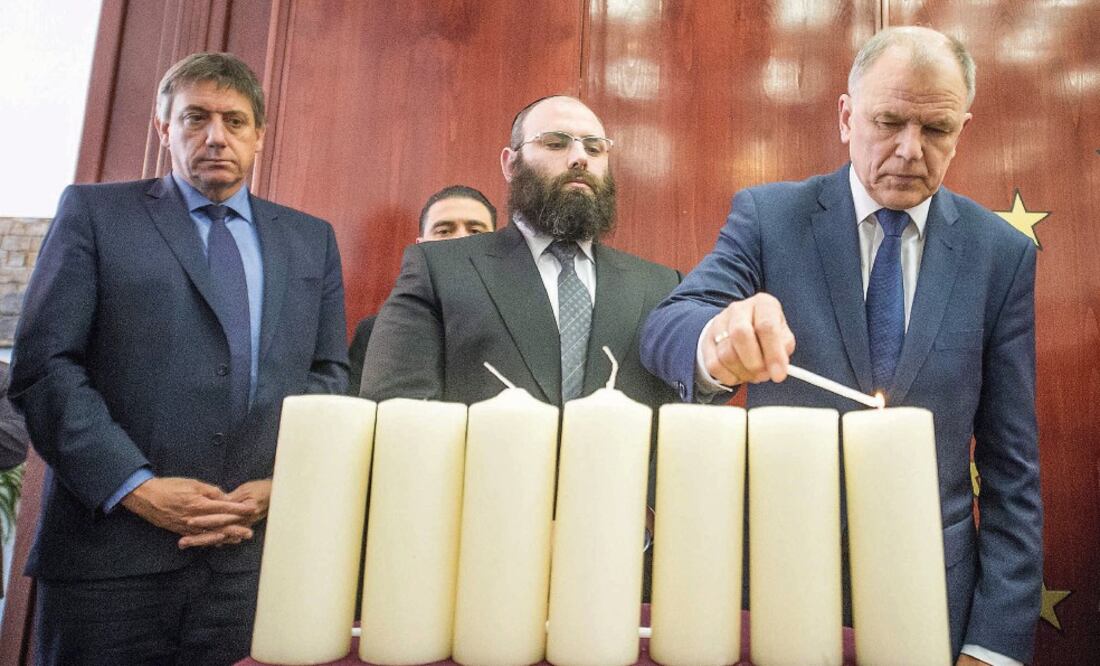 El comisario europeo de Salud, Vytenis Andrukaitis, enciende una vela en presencia del ministro de Interior belga, Jan Jambon (izq.) y del rabino Menachem Margolin, en una ceremonia en recuerdo de las víctimas del 22-M, ayer en Bruselas (EFE)