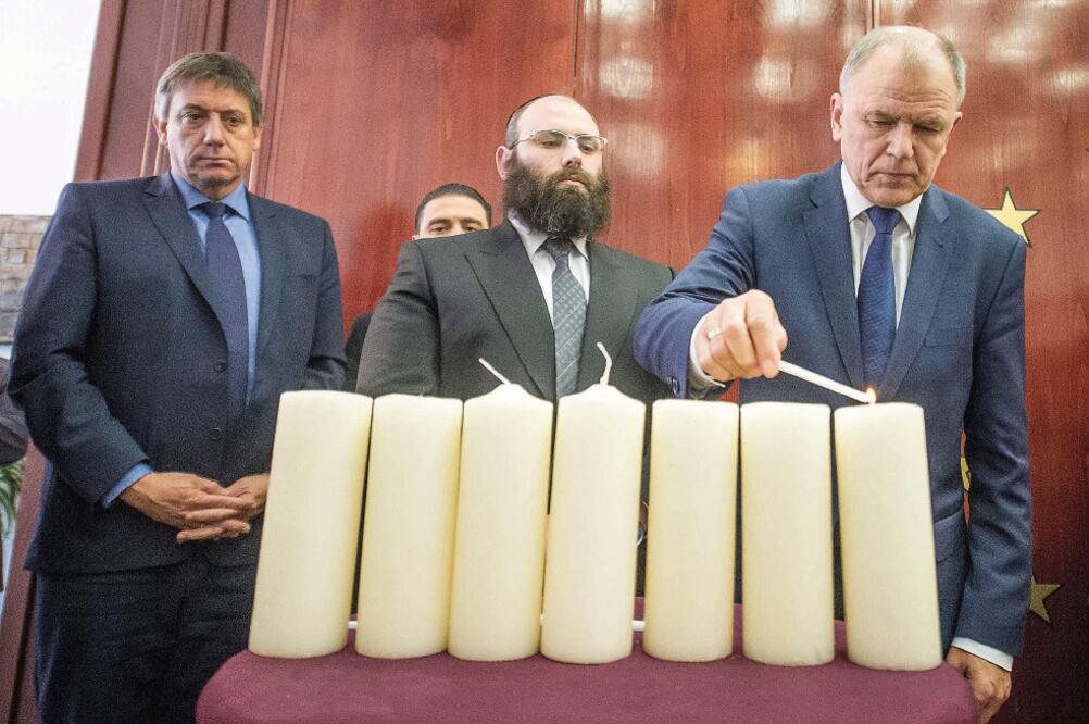 El comisario europeo de Salud, Vytenis Andrukaitis, enciende una vela en presencia del ministro de Interior belga, Jan Jambon (izq.) y del rabino Menachem Margolin, en una ceremonia en recuerdo de las víctimas del 22-M, ayer en Bruselas (EFE)