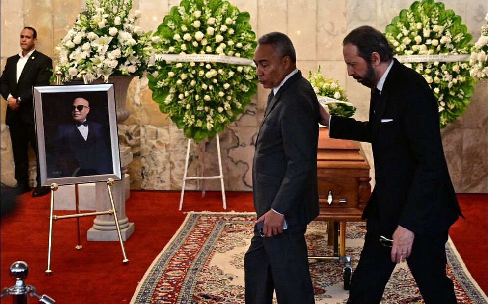 El cantante y compositor dominicano Juan Luis Guerra (der.) y el periodista Severo Rivera asisten al velatorio del merenguero Rubby Pérez, quien falleció tras el derrumbe del techo de la discoteca Jet Set, en el Teatro Nacional de Santo Domingo, el 10 de abril de 2025. Foto: AFP