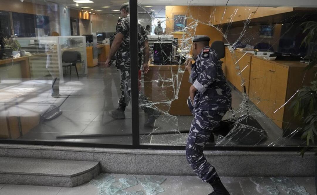 Policías libaneses entran a un banco a través de una ventana que rompieron depositantes al salir luego de tratar de obtener su dinero. Foto: AP