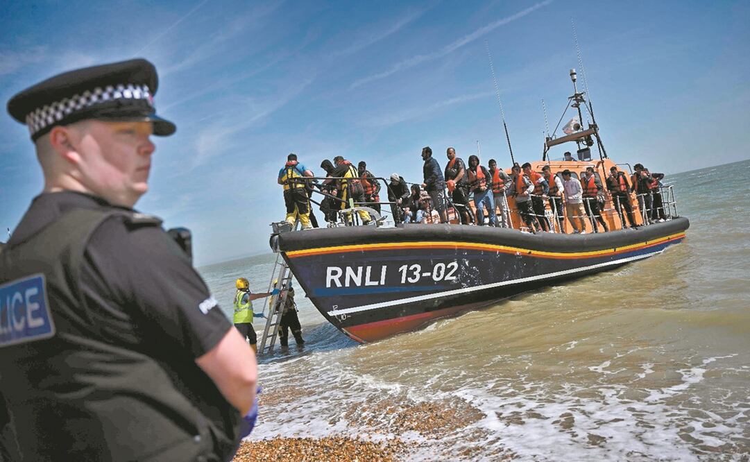  Un oficial británico en la playa de Dungeness, en la costa sureste de Inglaterra, el 15 de junio, mientras integrantes de la Royal National Lifeboat Institution ayudan a migrantes a desembarcar, después de que fueran recogidos en el mar mientras intentab