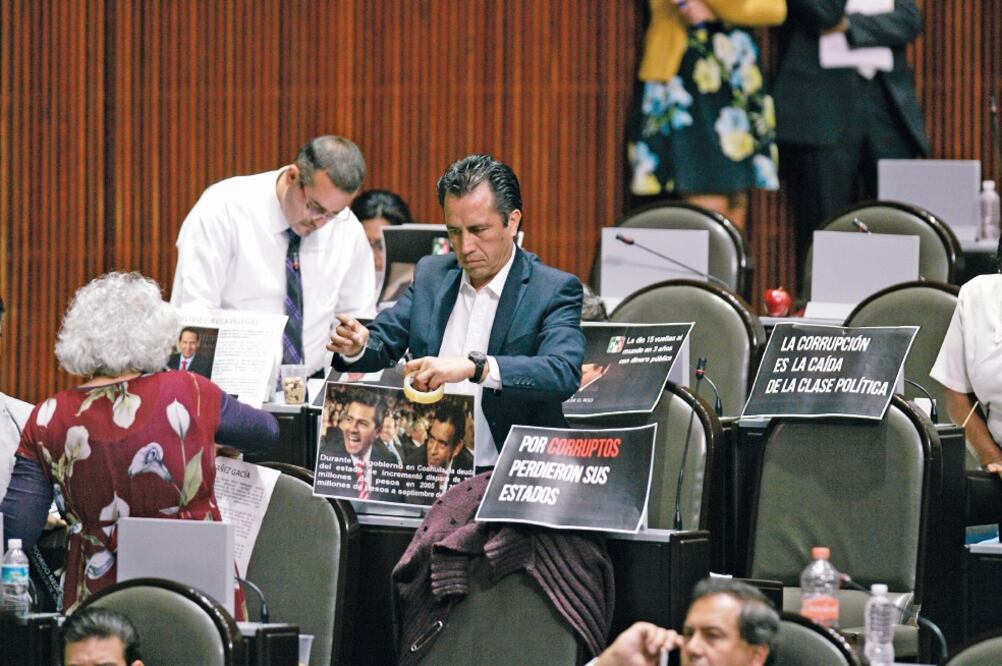 El diputado Cuitláhuac García (Morena) pega fotografías en protesta, durante la sesión del pleno de la Cámara de Diputados (ARCHIVO. EL UNIVERSAL)