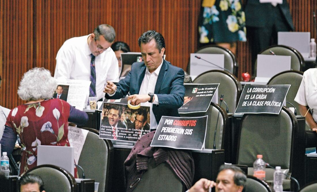 El diputado Cuitláhuac García (Morena) pega fotografías en protesta, durante la sesión del pleno de la Cámara de Diputados (ARCHIVO. EL UNIVERSAL)