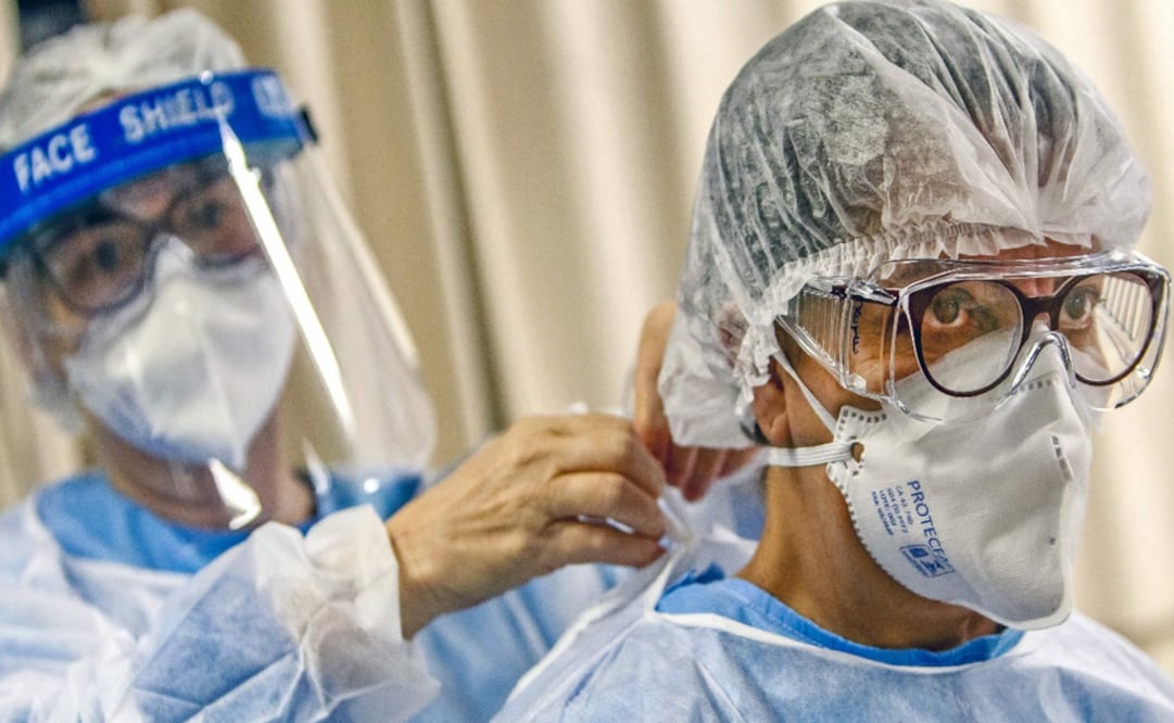A doctor puts a face mask on a colleague before treating patients infected with the novel coronavirus - Photo: Silvio Ávila/AFP