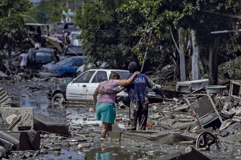 Un elemento de la Marina de México ayuda a una mujer a cruzar una calle inundada en Poza Rica, estado de Veracruz, México. (AP Foto/Félix Márquez)