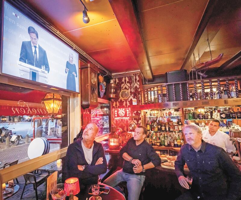 Empleados de un local en Ámsterdam ven el anuncio del gobierno en el que se anunció un “confinamiento parcial” por el rebrote de coronavirus. Entre las medidas se incluyen el cierre de bares y restaurantes. REMKO DE WAAL. AFP