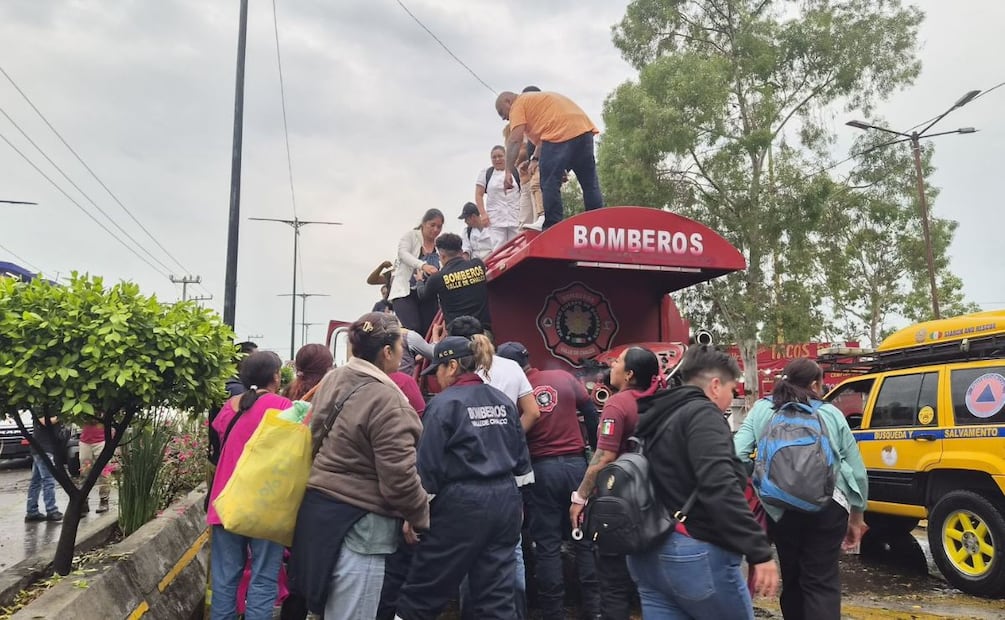 Bomberos ayudan a los vecinos de Valle de Chalco a pasar la zona inundada de la avenida Cuauhtémoc. | Foto: Especial.