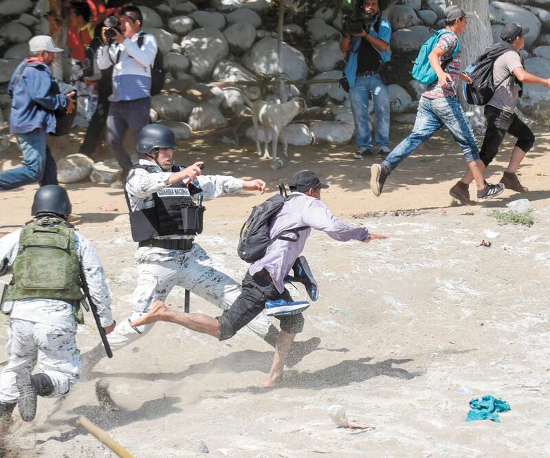 Polémica. La imagen de un elemento de la GN poniendo el pie a un migrante fue cuestionada en redes sociales. JOHAN ORDOÑEZ. AFP