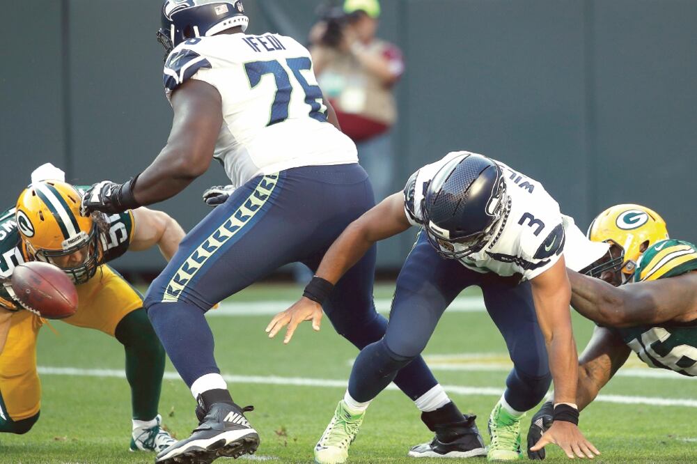 Russell Wilson (3), sufrió toda la tarde la presión de la defensa packer (JOE ROBBINS. AFP)