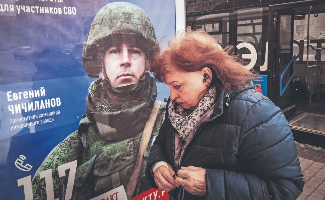 Una mujer junto a un anuncio que promueve el servicio militar por contrato, en el oeste de Moscú. Foto: de ALEXANDER NEMENOV. AFP