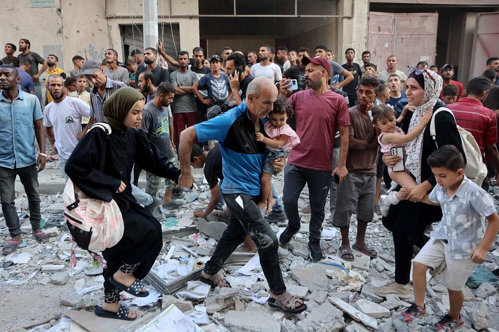 Un hombre palestino evacua el lugar de un ataque israelí contra varios edificios en el barrio de Al-Rimal, en la ciudad de Gaza, mientras la gente se reúne para inspeccionar los daños. Foto: AFP