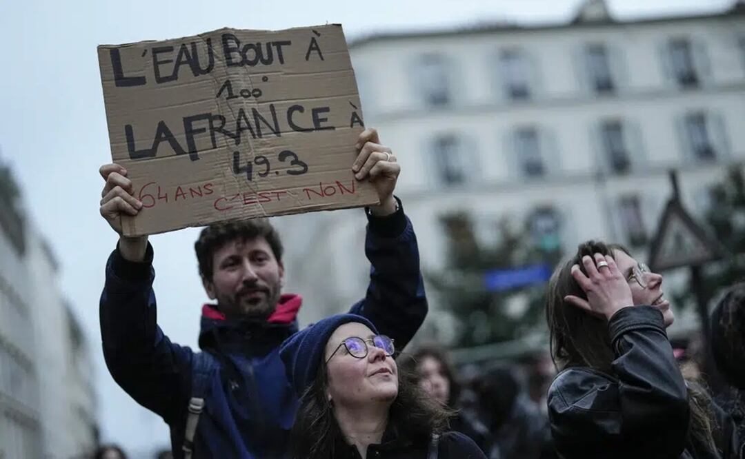 Un manifestante alza un cartel que dice "el agua hierve a los 100 grados, Francia hierve a los 49,3. 64 años es no", durante una protesta en París. Foto: AP