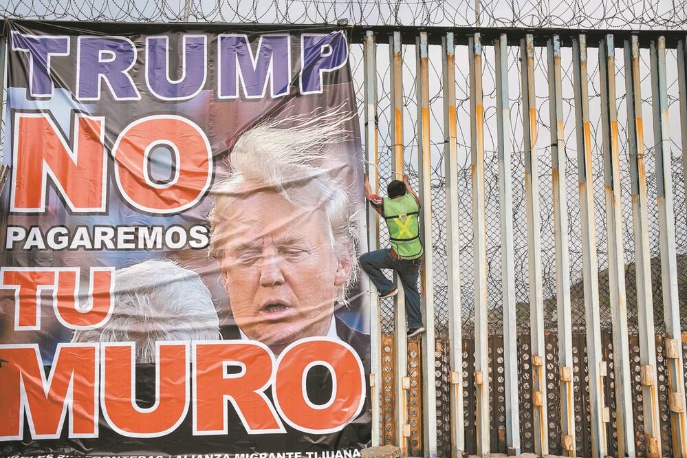 Un miembro del grupo Ángeles de la Frontera coloca una pancarta donde se lee: “Trump, no pagaremos por tu muro”, durante una manifestación en contra del mandatario estadounidense en Playas de Tijuana, Baja California. Foto:  GUILLERMO ARIAS. AFP 