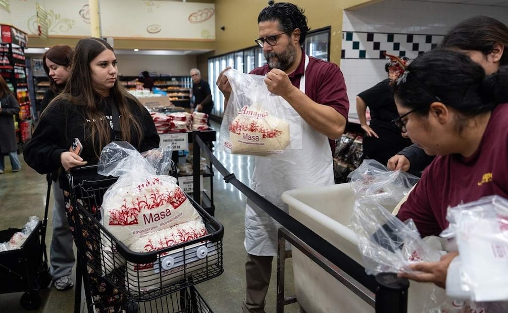 El gerente de tienda, Adrien Arriaga, carga bolsas de masa, utilizada para hacer tamales, en el carrito de compras de Alexa Campos en el mercado Amapola en Downey, California. Foto: Jae C. Hong. AP