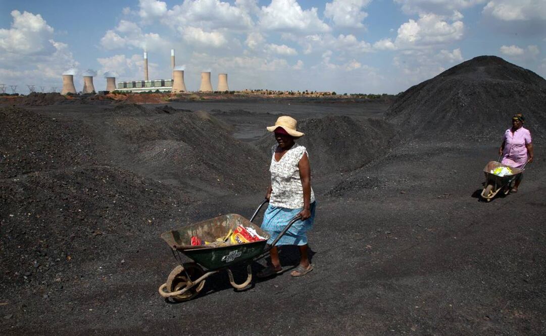 Mujeres empujan carretillas sobre un vertedero de carbón en la central eléctrica de Duvha, al este de Johannesburgo, Sudáfrica. Foto: Dennis Farrell. AP
