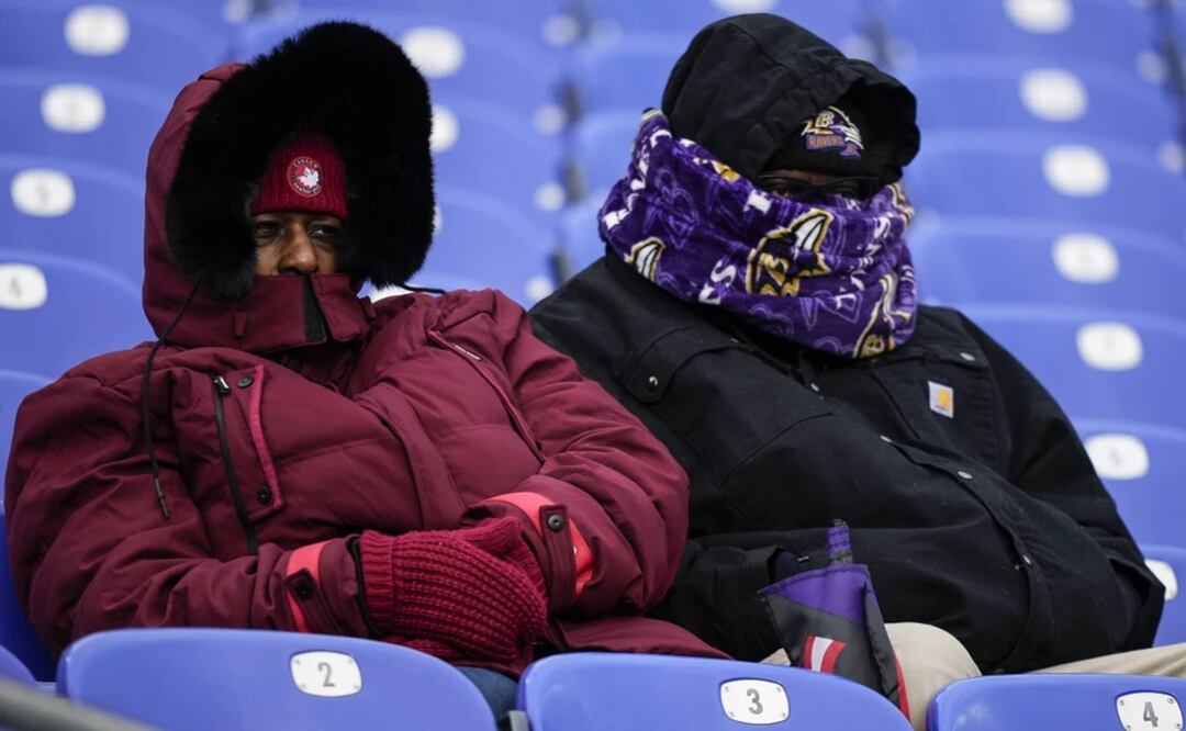 Dos personas de cobijan del frío en el partido de fútbol americano entre los Ravens de Baltimore y los Texans de Houston, en Baltimore, el 20 de enero de 2024. Foto: AP