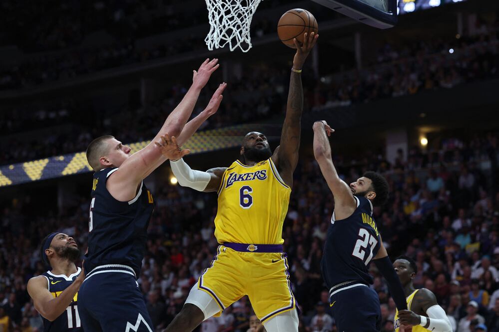 LeBron James se levanta entre Nikola Jokic y Jamal Murray / Foto: AFP