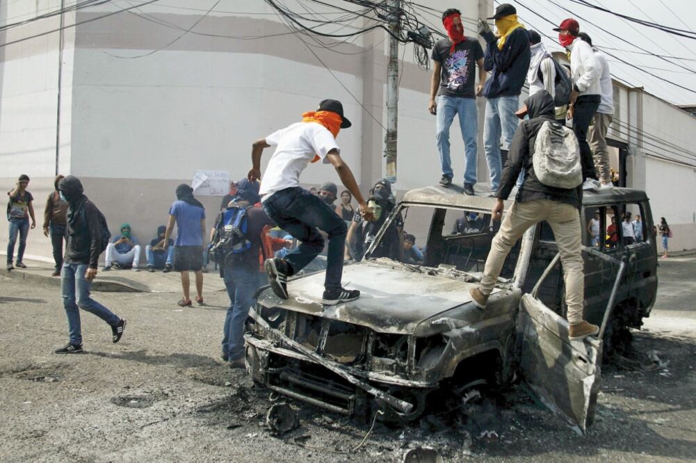 Manifestantes brincan sobre una camioneta quemada, durante una protesta, ayer, contra el gobierno de Nicolás Maduro, en Venezuela (CARLOS E. RAMÍREZ. REUTERS)