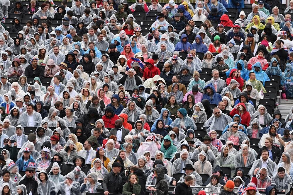 Espectadores, mientras esperan que el Rey Carlos III y la reina Camila salgan del Palacio de Buckingham hacia la Abadía de Westminster, en Londres. Foto: EFE