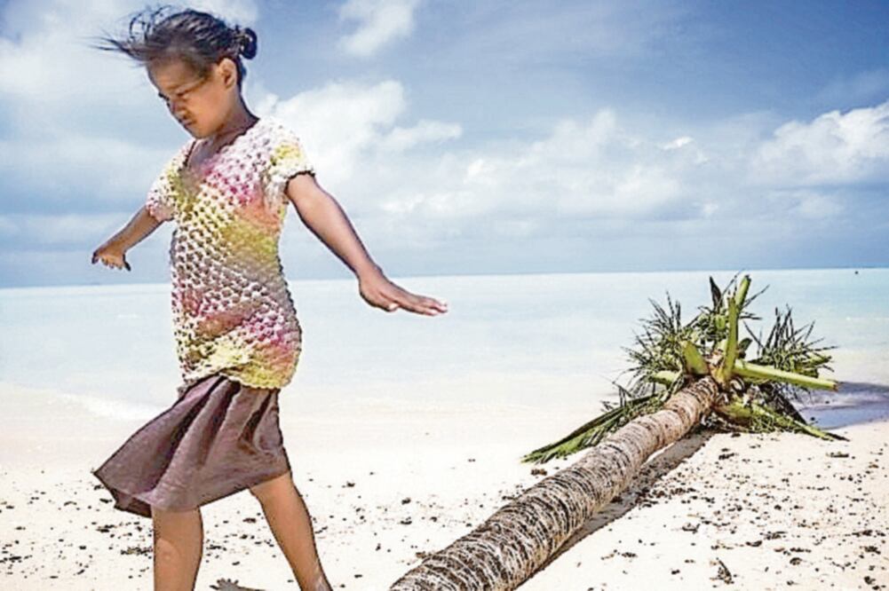 Una niña juega en una playa en Kiribati, que podría perder parte de su superficie terrestre a causa del aumento del nivel del mar en este siglo.