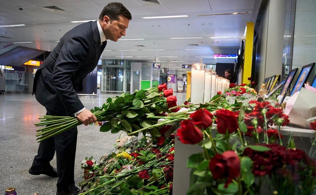 Vladímir Zelenski, presidente de Ucrania, deja flores a los retratos de la tripulación que viajaba en el Boeing 737 de Ukraine International Airlines. Foto: EFE