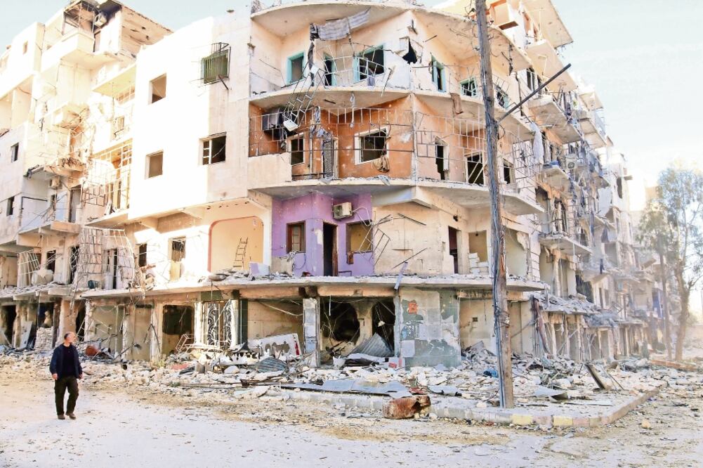 Un sirio pasa junto a edificios destruidos en la asediada ciudad de Aleppo (ABDALRHMAN ISMAIL. REUTERS)