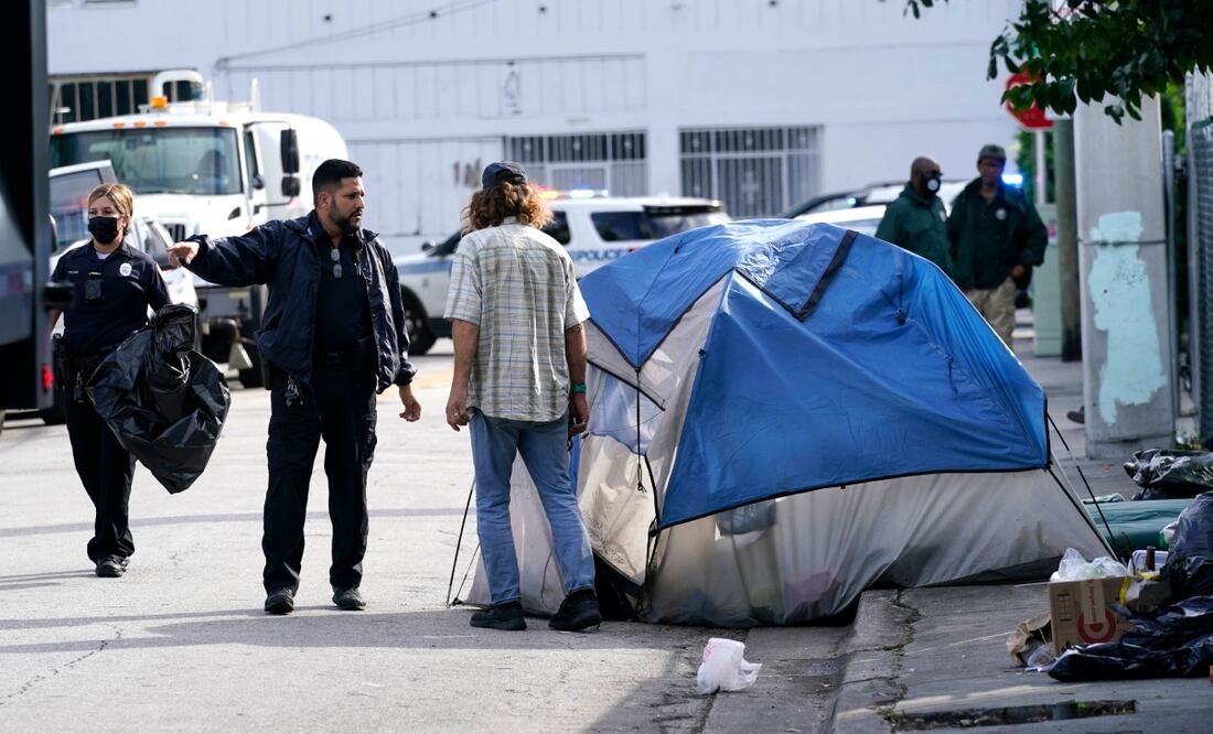 Un oficial de policía de la ciudad de Miami habla con una persona sin hogar, antes de una limpieza de la calle, el martes 16 de noviembre de 2021, en Miami. Foto: AP/ARCHIVO