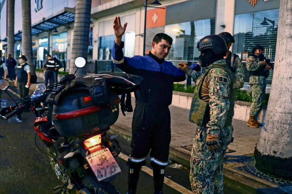 Un integrante del ejército revisa a un hombre en motocicleta en un puesto de control en una calle de Guayaquil, el lunes pasado.