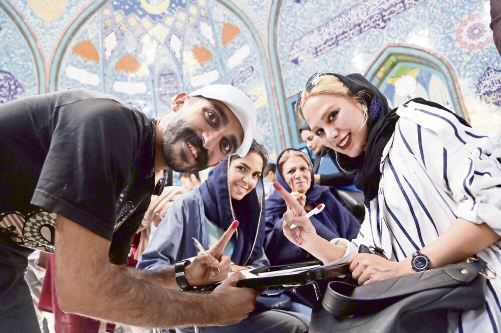 Iraníes muestran sus dedos marcados con tinta después de votar en un colegio electoral de Teherán. Estos lugares cerraron hasta la media noche debido a la gran afluencia de votantes. (ABEDIN TAHERKENAREH. EFE)