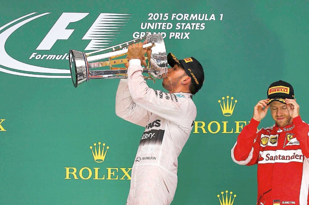 En lo más alto del podio, el piloto británico Lewis Hamilton bebió la champaña en la gran copa obtenida para celebrar su triunfo y el campeonato (MIKE STONE. REUTERS)