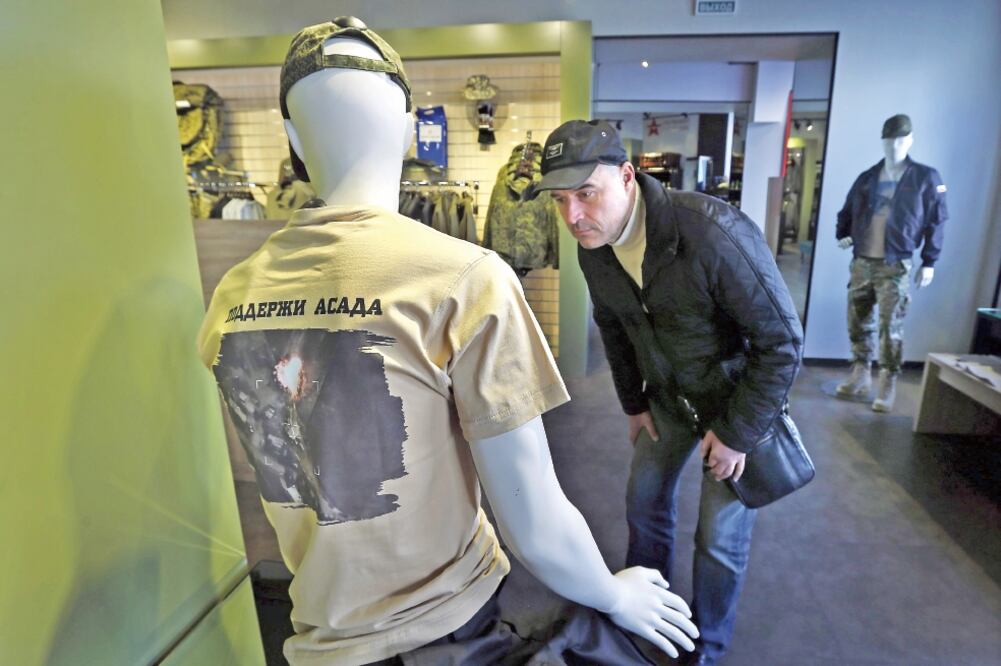 Un hombre observa una camiseta con la imagen de un bombardeo ruso en suelo sirio y un mensaje de apoyo a Al-Assad”, en una tienda en Moscú (YURI KOCHETKOV. EFE)