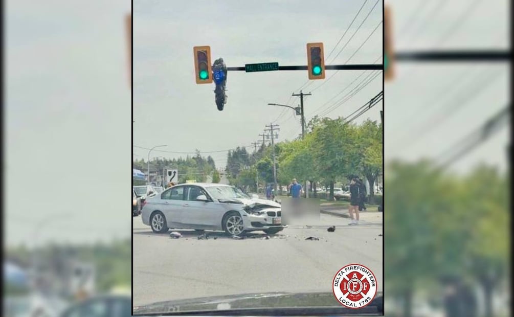 En Delta, Canadá chocaron un motociclista y un vehículo, provocando que la moto quedara colgada del semáforo. Foto: Departamento de bomberos de Delta