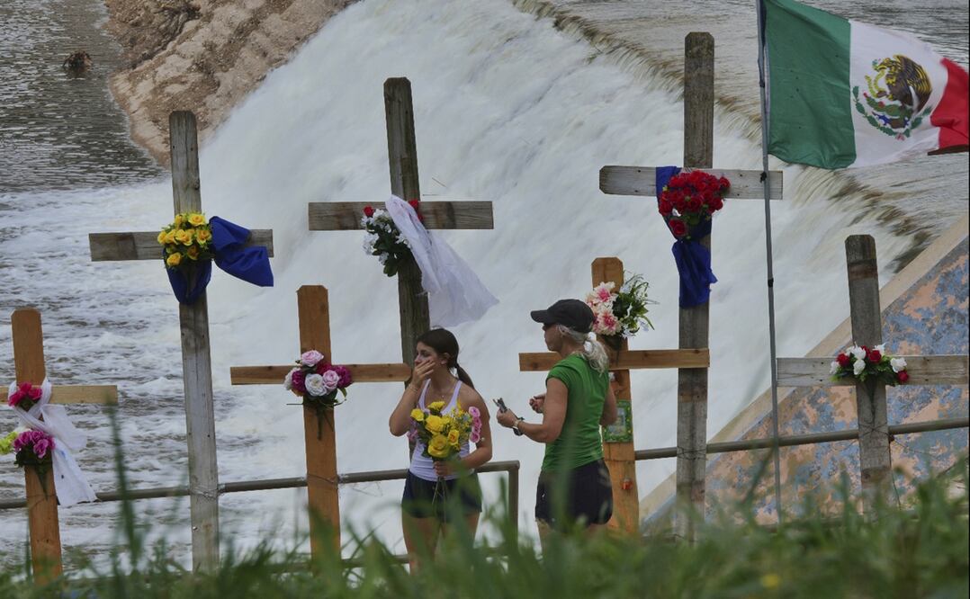 Lara Merritt (d) y su hija Rylee depositan flores en un monumento improvisado para las víctimas de las inundaciones, instalado a orillas del río Guadalupe, en Kerrville, Texas, el sábado 12 de julio de 2025. Foto AP