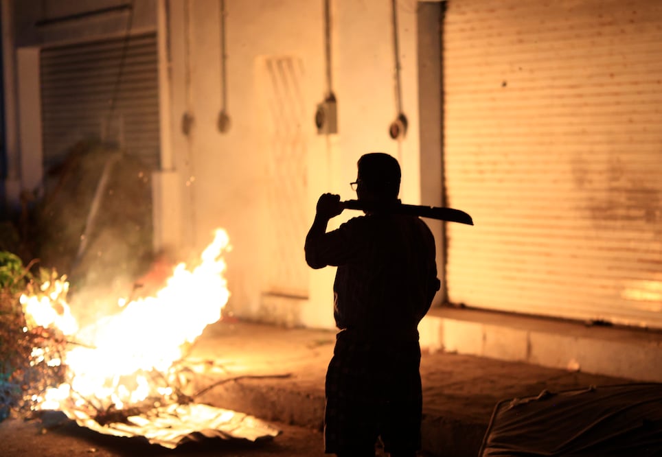 Con machete al hombro, un hombre monta guardia afuera de su casa para evitar que entren a robar, pues crece la desesperación ante la falta de alimentos y servicios. Foto: David Guzmán | EFE