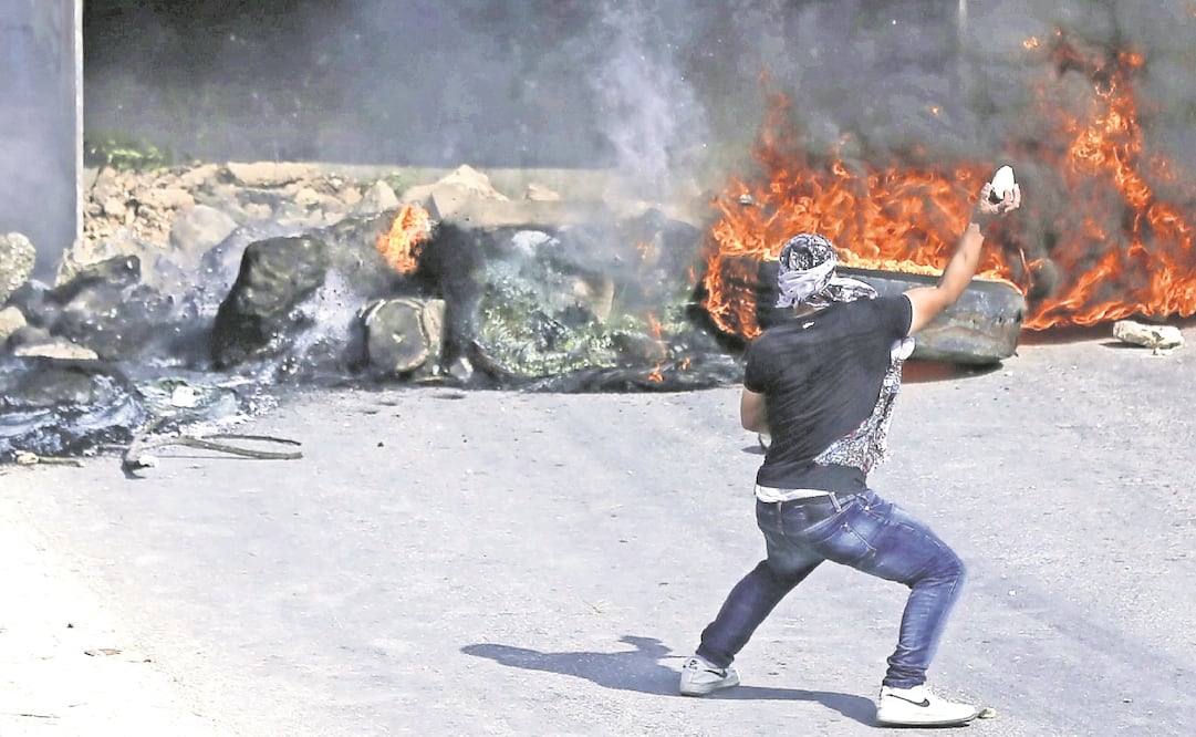 Enojo. Un palestino lanza una roca a un bulldozer israelí durante enfrentamientos en Kubar, al oeste de Ramalá. FOTO: ABBAS MOMANI. AFP