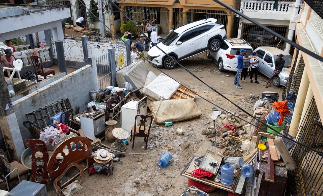 Personas quitan el lodo de sus muebles, junto a varios vehículos que fueron arrastrados por la corriente, hoy en Santo Domingo (República Dominicana). Foto: EFE